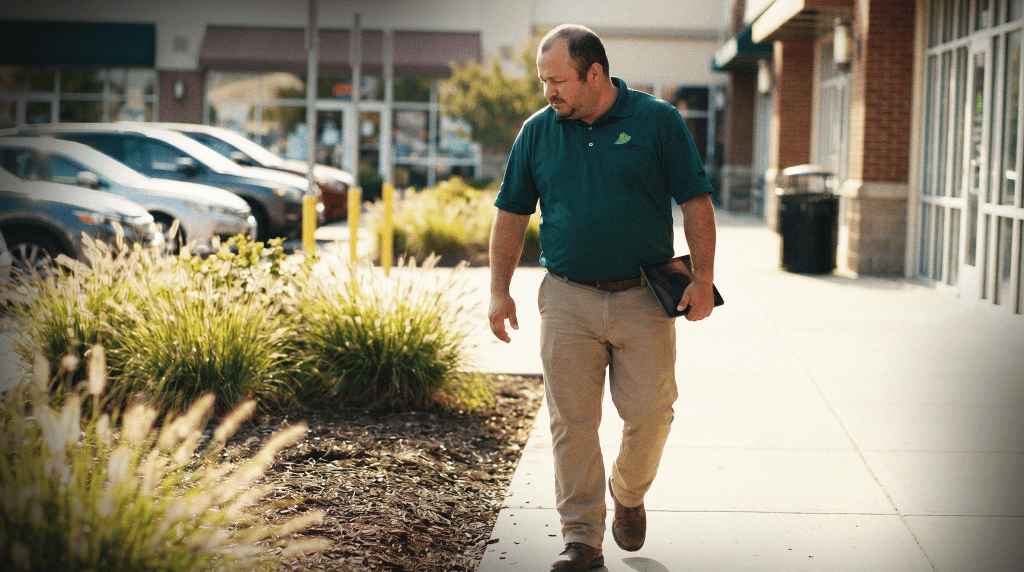 Green Empire team member reviewing a walkthrough checklist on a tablet outside a commercial office building.